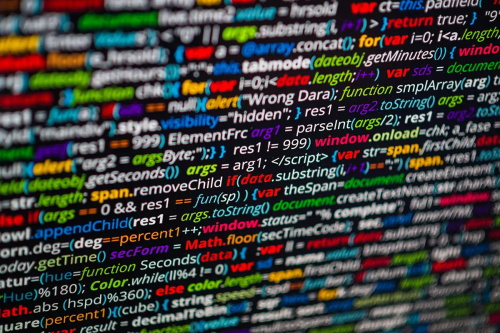 Close-up blurred shot of colorful JavaScript source code on dark background